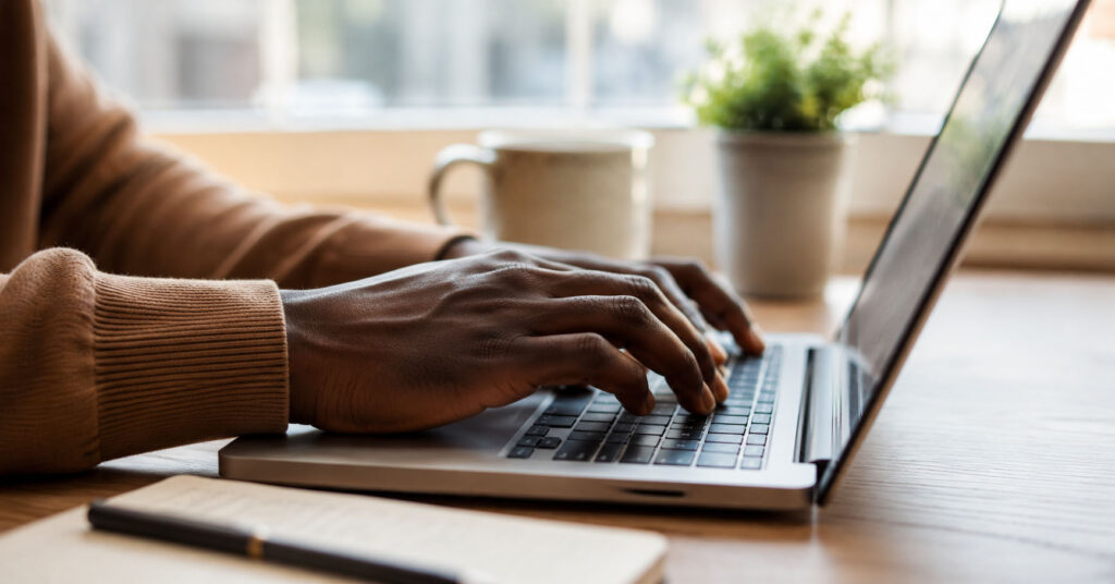 Close up of young African hands typing on a laptop completing an online task