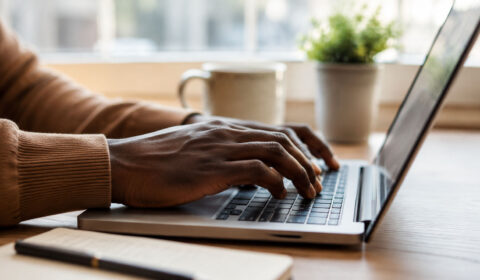 Close up of young African hands typing on a laptop completing an online task